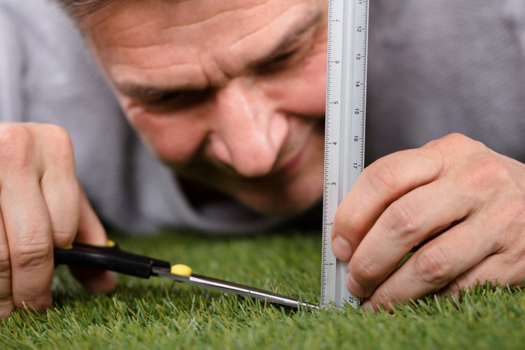 Man trying to cut grass perfectly
