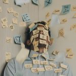 An over extended, stressed business man has a bunch of "to-do" post its stuck to his body. He needs help practicing stress management.